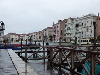Pier at grand canal by buildings against sky
