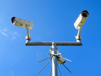 Low angle view of camera pole against clear blue sky