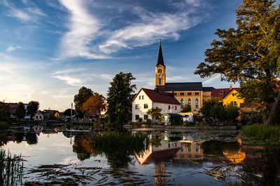 Reflection of buildings and trees in lake against sky