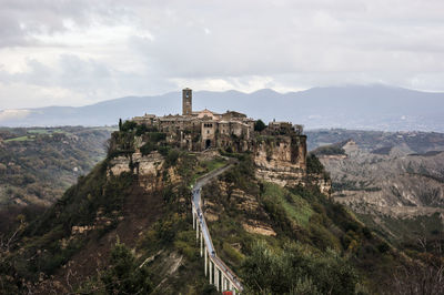 Castle on mountain against cloudy sky