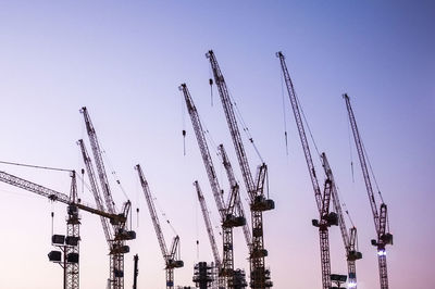 Low angle view of silhouette cranes against sky