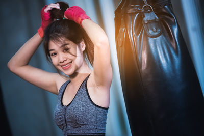 Portrait of smiling woman standing by boxing bag