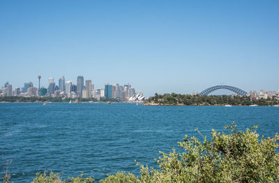 Scenic view of river by city buildings against clear sky