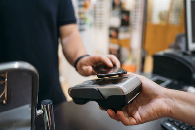 Mid adult man making contactless payment through mobile phone
