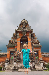 Young woman jumping in front of a temple building