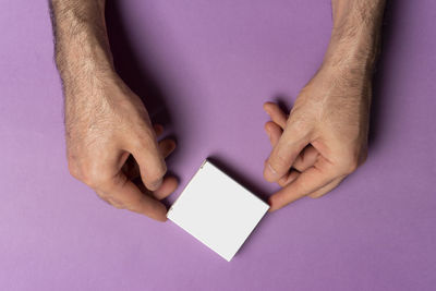 Cropped hand of woman holding credit card against blue background