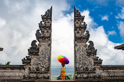 Rear view of woman standing with umbrella at temple entrance