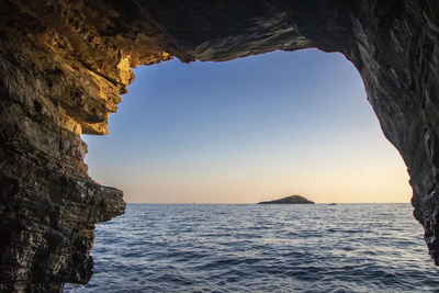 Rock formation in sea against clear sky