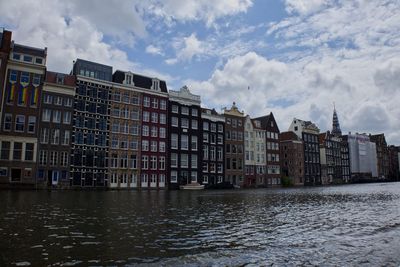 Buildings by river against sky