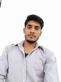 Portrait of young man standing against white background