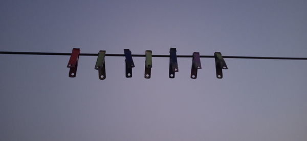 Low angle view of clothespins hanging on clothesline against sky