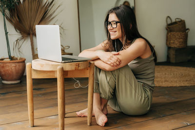 A young brunette woman is watching a video and talking on a video call using a laptop.