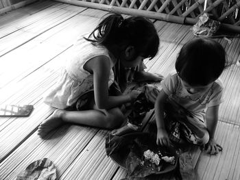 High angle view of children having food while sitting on wooden floor