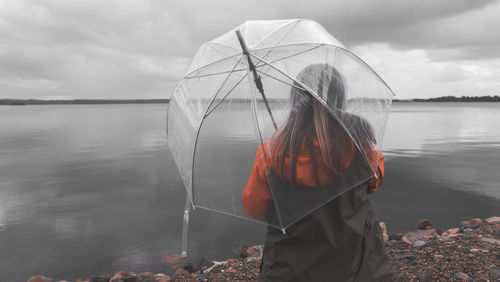 Rear view of woman standing on beach against sky