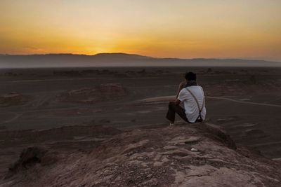 Rear view of man on sand at sunset