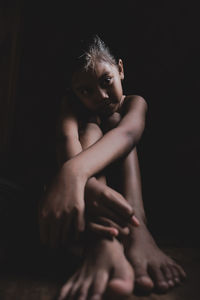 Girl sitting against black background
