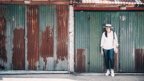 Young woman standing against corrugated iron