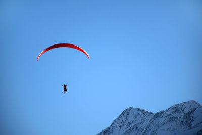 Low angle view of person paragliding against clear blue sky