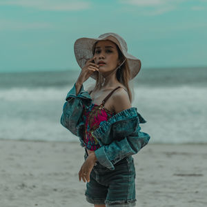 Young woman wearing hat while standing on beach