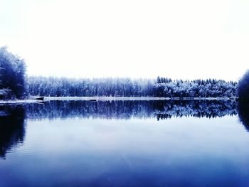 Reflection of trees in lake against clear sky