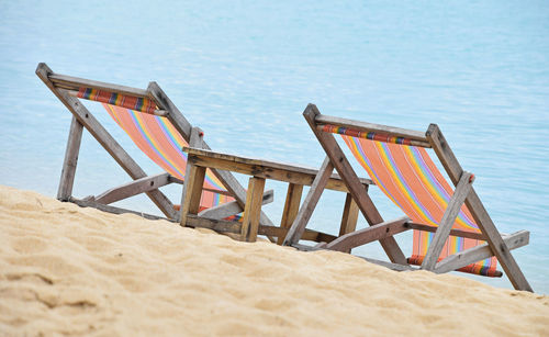 Deck chairs on beach against sea