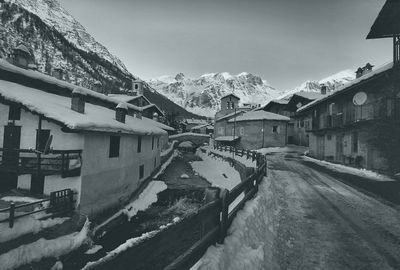 Snow covered houses by buildings in city against sky