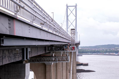 Bridge over river in city against sky