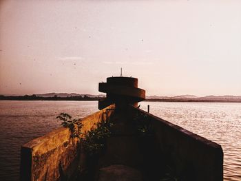 Pier over sea against clear sky during sunset