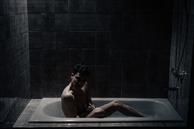 Full length of shirtless man sitting in pool