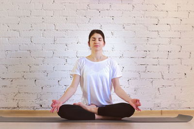 Full length of woman sitting against wall