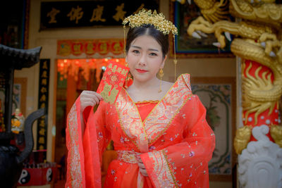 Portrait of young woman in traditional clothing standing at shrine