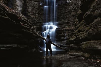 Rear view of man standing by waterfall