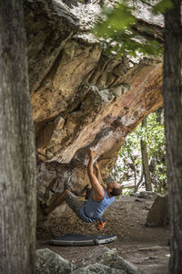 Full length of man sitting on tree trunk