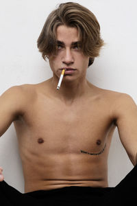 Portrait of young man smoking over white background