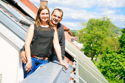 Portrait of smiling young woman standing on railing