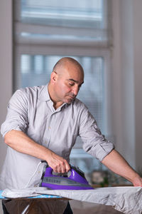 Man ironing clothes at home