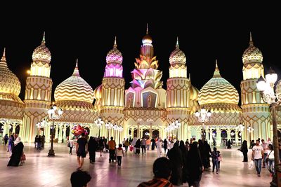 People at illuminated temple against clear sky at night