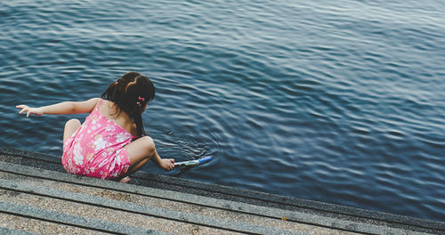 Full length of girl crouching by lake