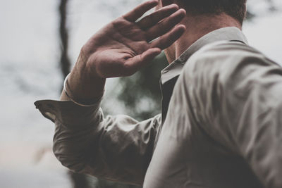 Side view of man gesturing against sky