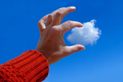 Low angle view of human hand against blue sky