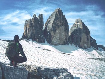 Man backpacker sit and watch popular tre cime di lavaredo  sharp peaks massif. alps,  italy,  europe