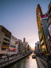 River amidst buildings in city against sky during sunset