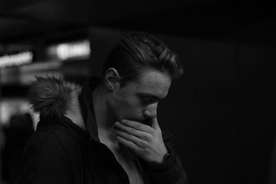 Close-up of thoughtful young man wearing fur hood at night