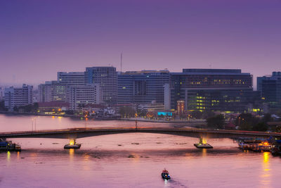 View of river and illuminated buildings against clear sky. chao phraya river.