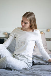 Young woman sitting on bed at home