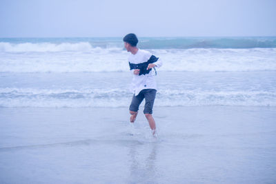 Full length of boy standing on beach against sky