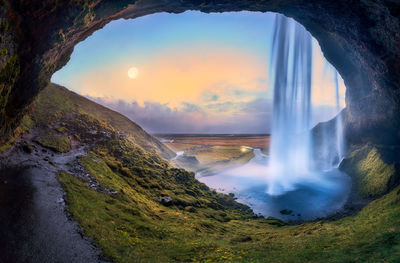 Scenic view of waterfall against sky during sunset