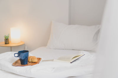 Book and crockery on bed at illuminated home