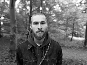 Portrait of man with tree trunk in forest