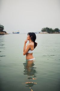 Side view of sensuous young woman wearing bikini in sea